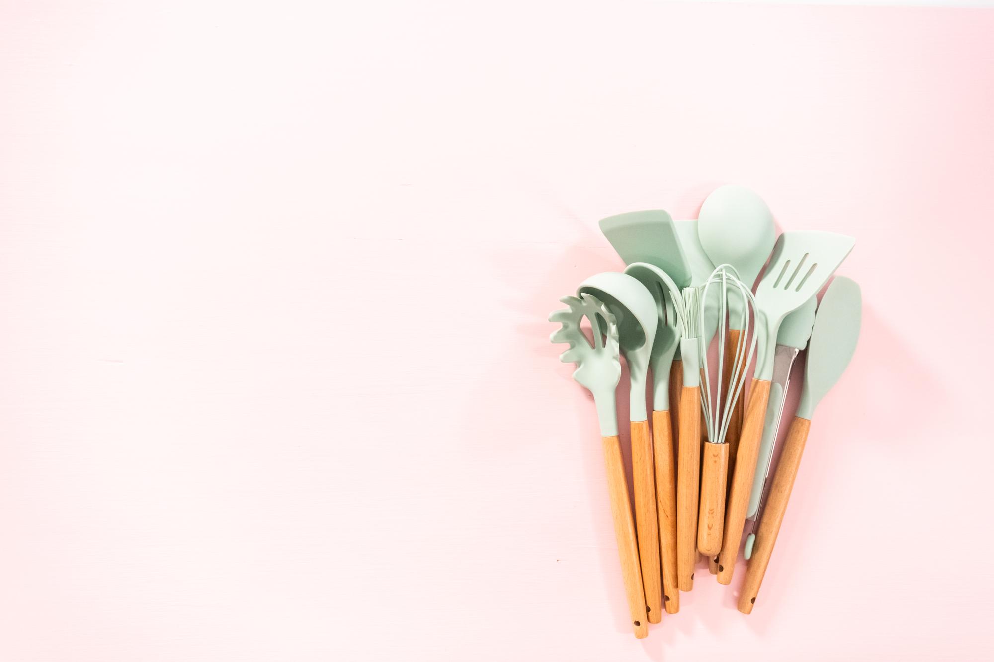 Assorted cooking tools on pastel surface